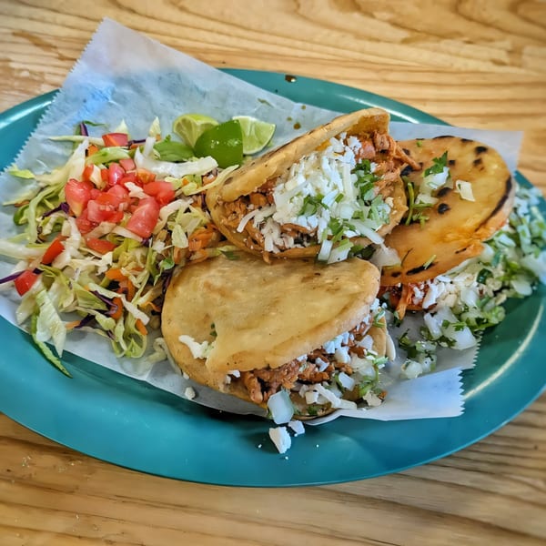 Three Los Homies Taqueria gorditas filled with meat, cheese, and cilantro, served with a side salad.