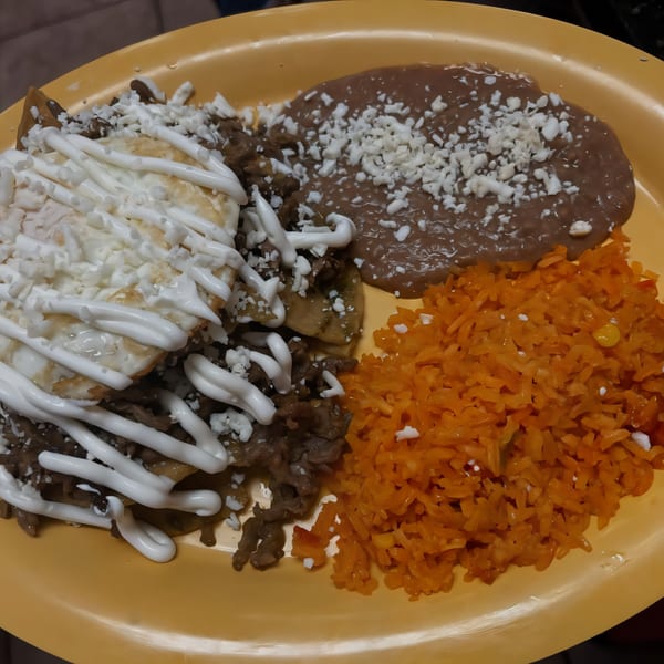 Los Homies Taqueria's Mexican dish with meat, beans, rice, and a fried egg topped with crema.